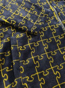 Primer plano del estampado puzzle en azul marino con líneas mostaza de la bata juvenil Muydemi de coralina.