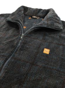 Primer plano del tejido polar verde oscuro de la bata corta Massana, con cuadros difuminados y un diseño informal de estilo juvenil.