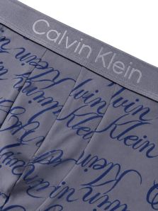Detalle del tejido de microfibra con estampado de logos Calvin Klein sobre fondo gris